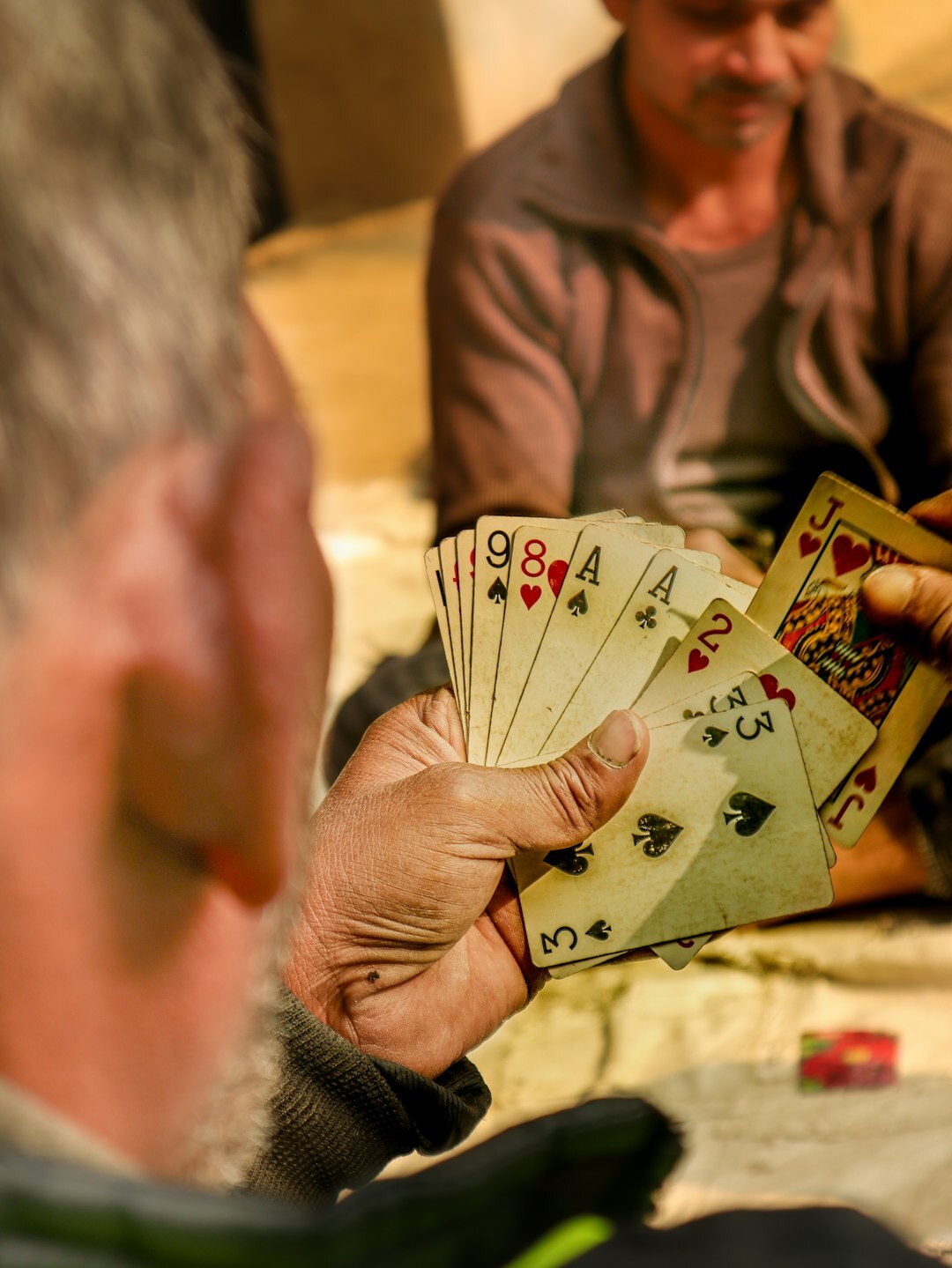 Group of elderly friends playing cards together at a table